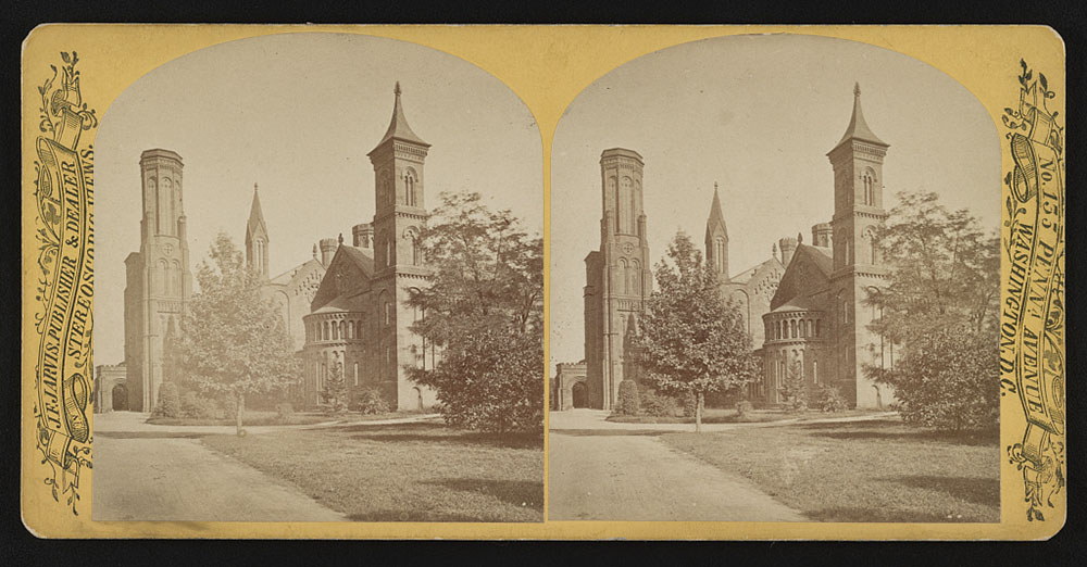 Sepia-toned stereoscope slide with two identical photographs side-by-side. The photos are of an imposing building in medieval revival style on a grassy, tree-lined campus.
