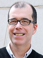 Headshot of a middle-aged white man with black hair and glasses