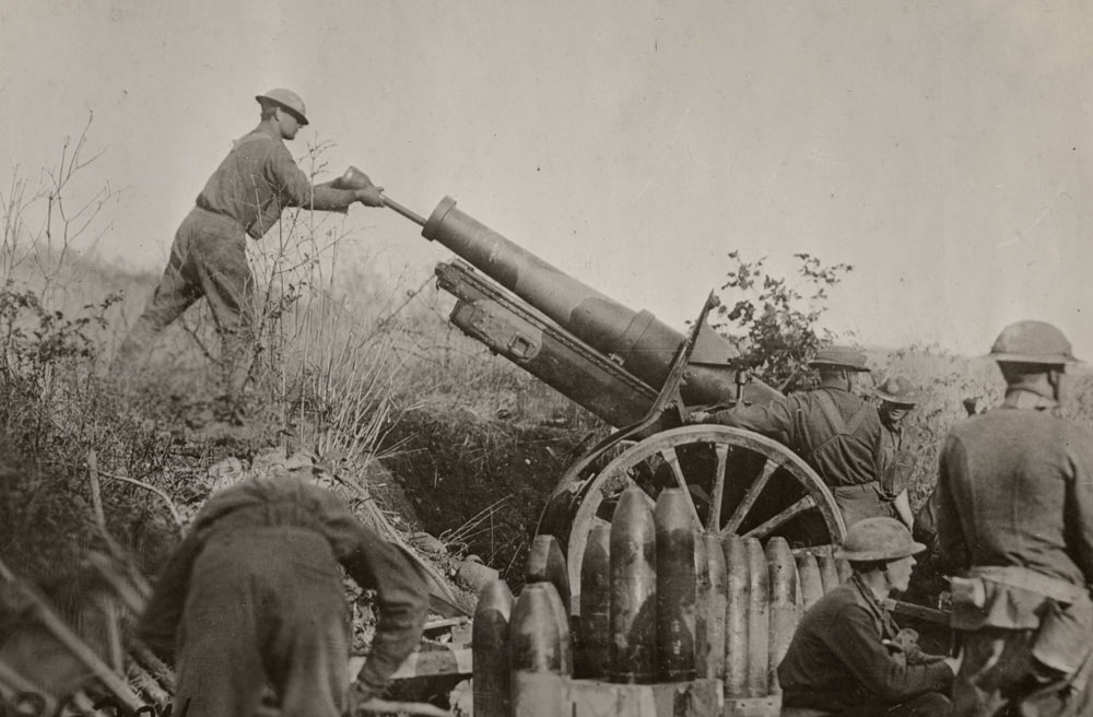 Des soldats entourent un obusier long et mince dans un bassin herbeux. Un soldat charge des munitions dans la partie commerciale de l'arme.