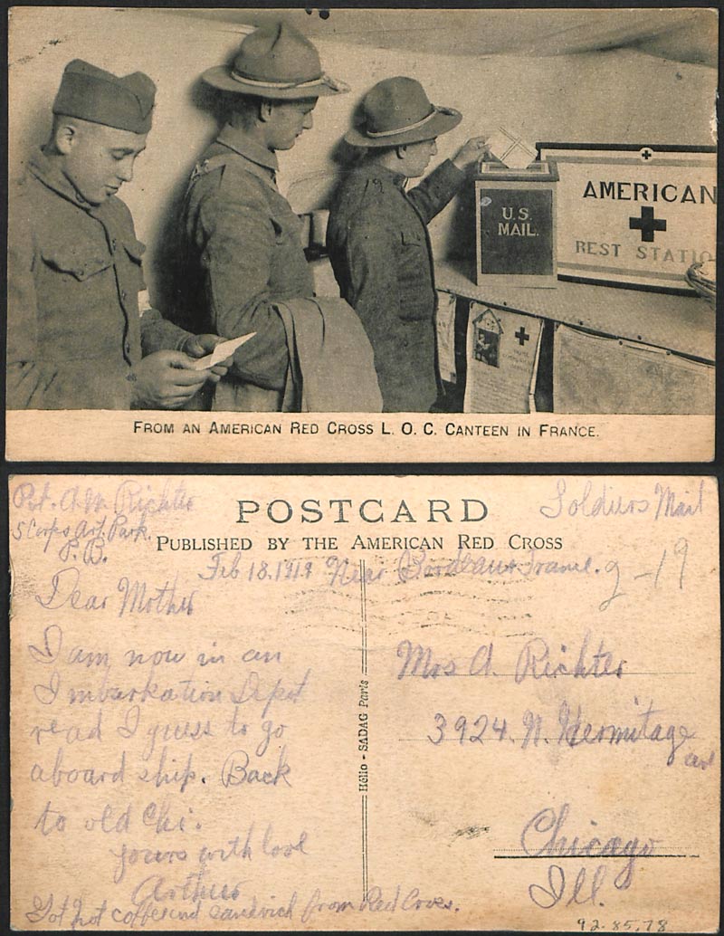 Scanned front and back of postcard. The front is a black and white photograph of three men in military uniform lined up in front of a box labeled 'U.S. Mail'. The back has messy cursive handwriting.