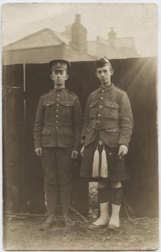 Black and white portrait of two young white men in military uniform. The one on the left wears trousers, the one on the right wears a kilt.