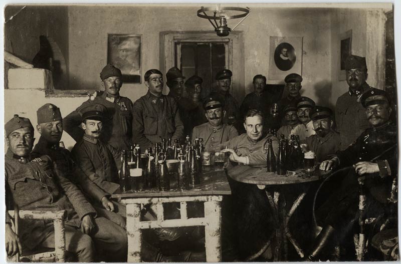 Grand groupe de soldats réunis autour de deux tables couvertes de bouteilles de bière.