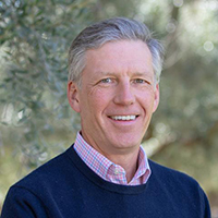 Headshot of a middle-aged cleanshaven white man with slicked-back silvering hair