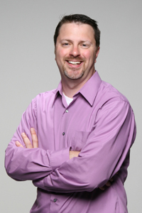 Headshot of a middle-aged white man with short dark hair and stubble
