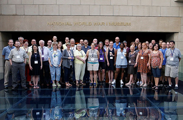Modern photograph of a large group of adults posing for a picture on the glass bridge inside the Museum.
