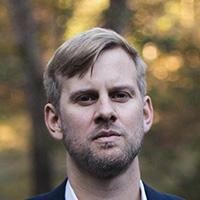 Headshot of a younger white man with blond hair and stubble.