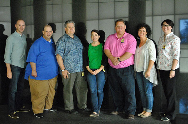 Modern photograph of a small group of adults posing for a picture in the entrance lobby of the Museum.