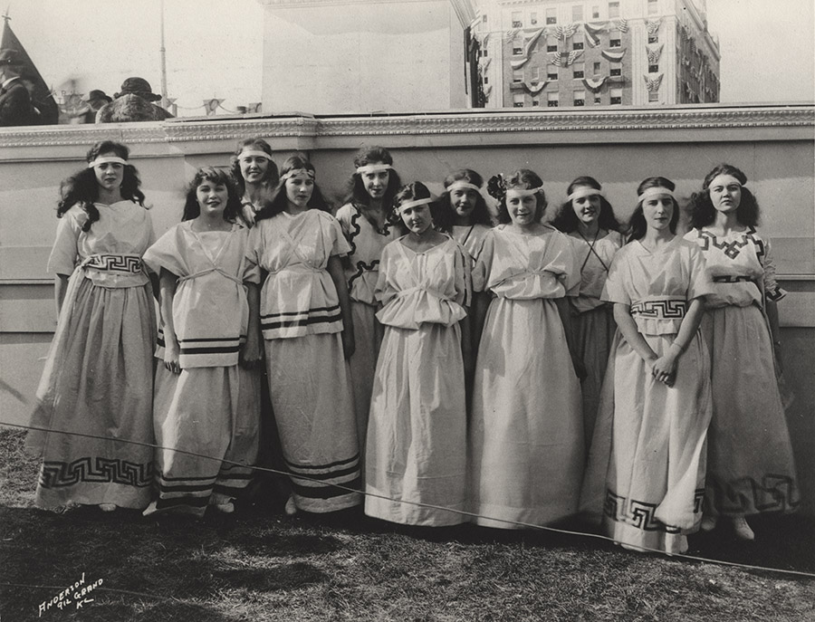Black and white photo of a group of young white women wearing classical Greek-inspired robes