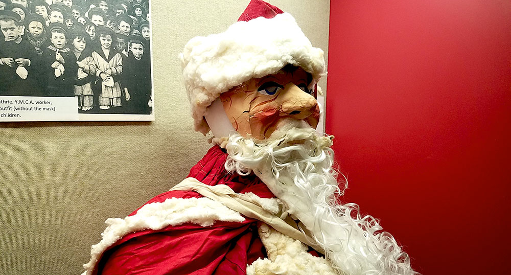 Photograph of a Santa Claus costume on a mannequin including a painted paper mask.
