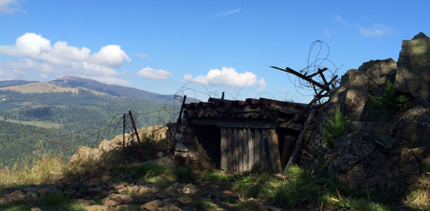 Modern photo of a destroyed bunker in the midst of a green valley on a sunny day.