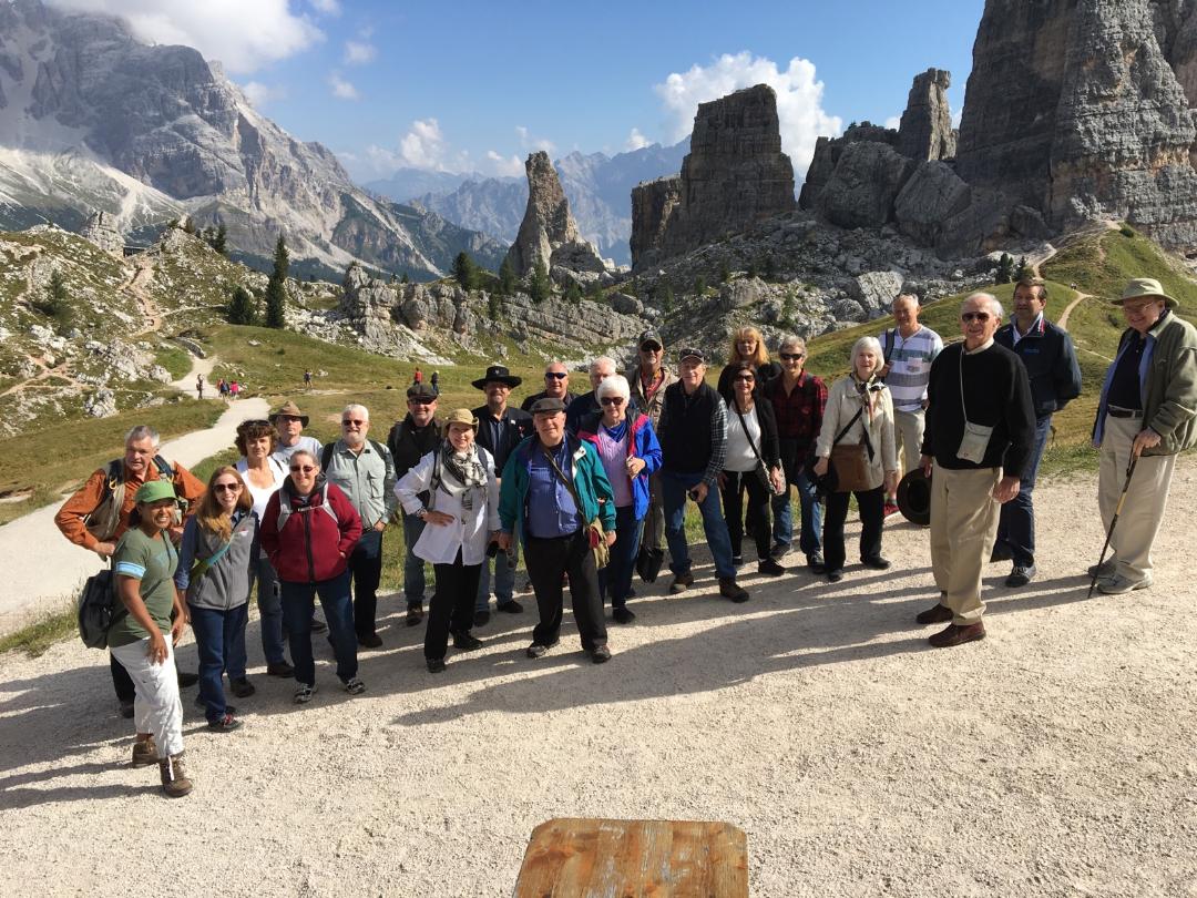 The tour group posing in front of a number of outcroppings and mountain peaks in the distance