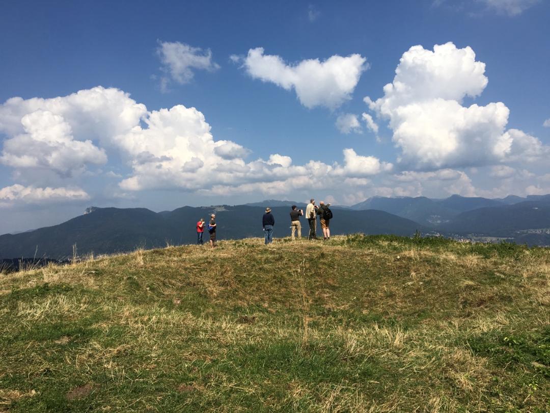 Atop a hill with low mountains in the background, a crater from a bomb explosion is still visible