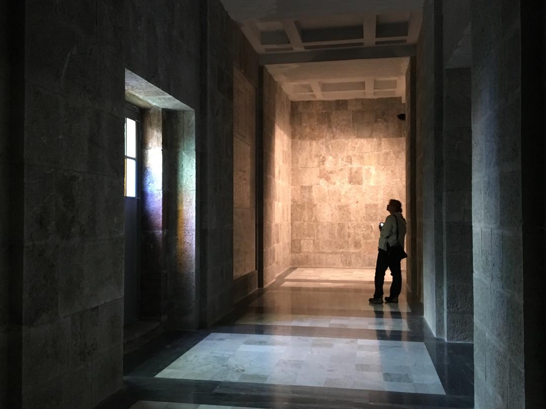 Inside a hall made of marble, cast in cool light and shadows.