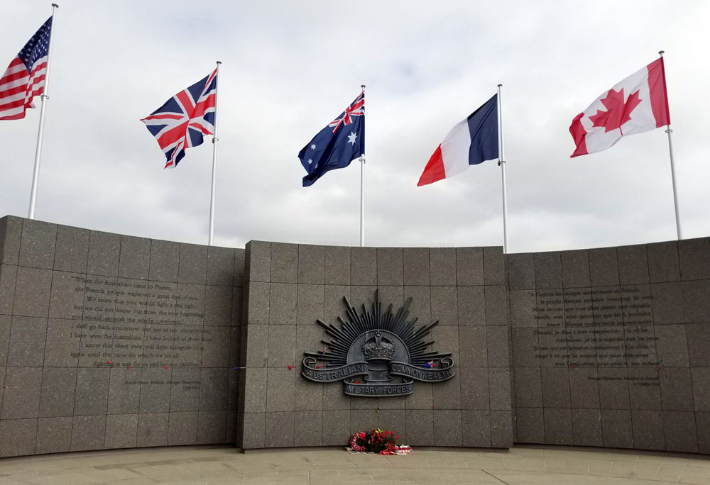 Photograph of a dark grey stone wall topped with flags.