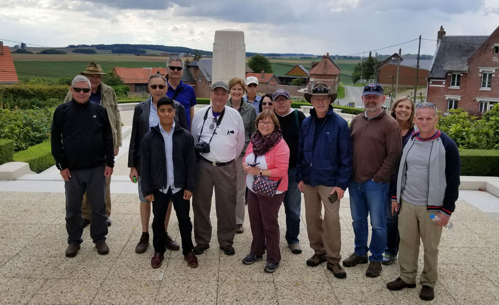 Photograph of a group of people posing in front of memorials and medieval buildings.