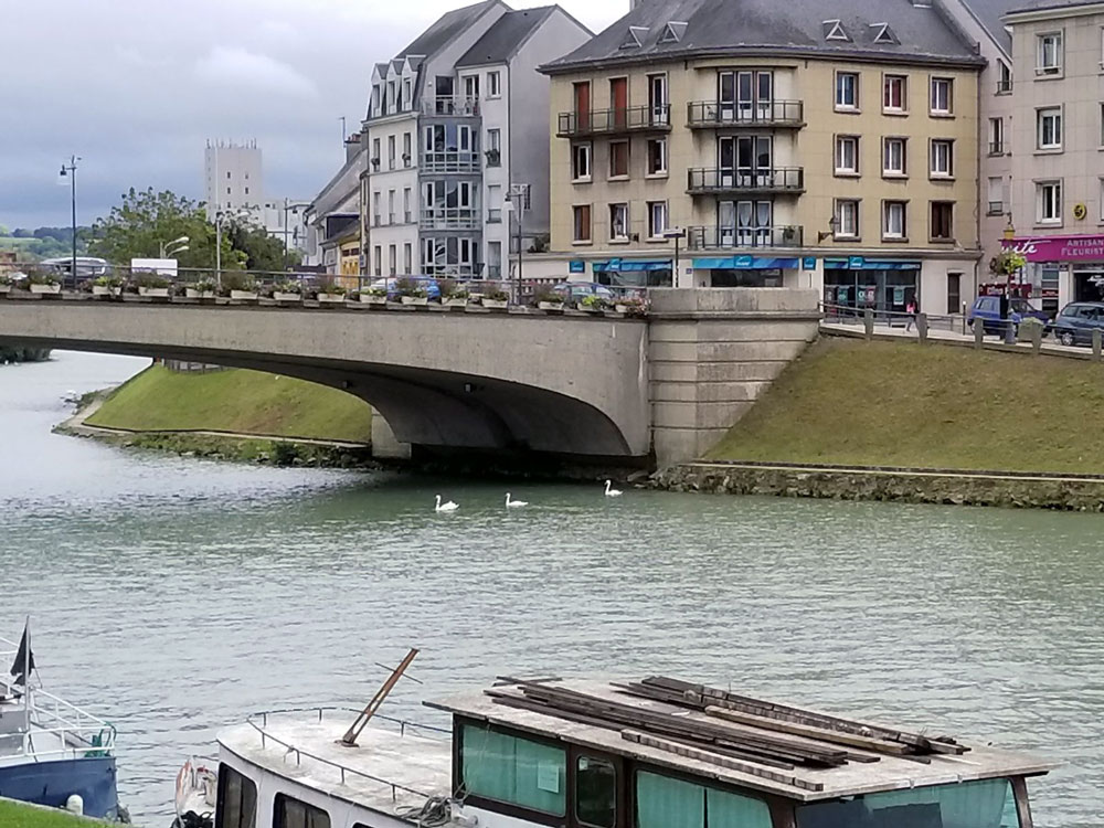 Photo of a bridge over a river with houseboats sailing under it.