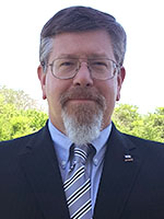 Headshot of a middle-aged white man with grey hair and goatee