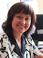 Headshot of a middle-aged white woman with brown hair wearing a black and white patterned shirt