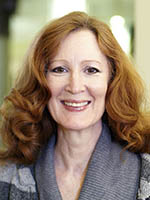 Headshot of a white woman with long red hair wearing a grey shirt