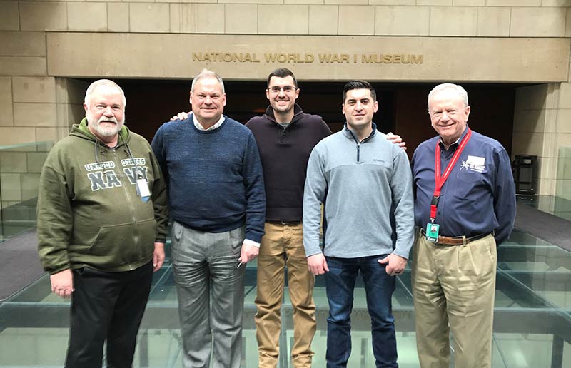 Group of white men spanning three generations standing on the glass bridge of the Museum.