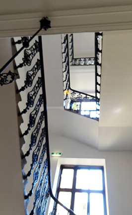 Looking up through an open staircase with wrought iron railings