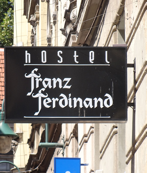 Black sign with white calligraphy text: 'hostel / franz ferdinand'