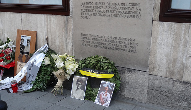 Wreaths, photographs, and other offerings lying under the stone plaque