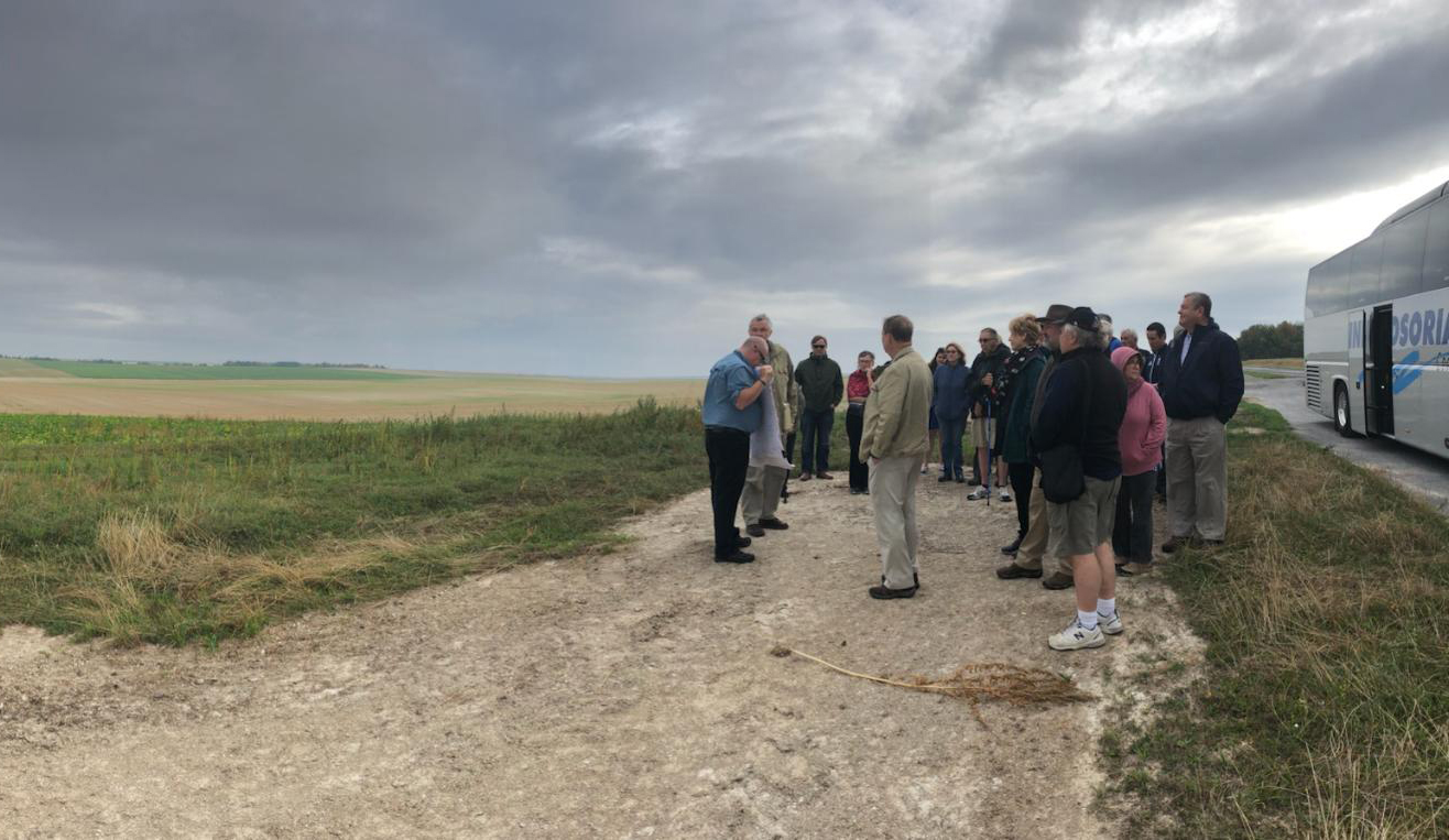 The tour group standing on the edge of a grassy field.