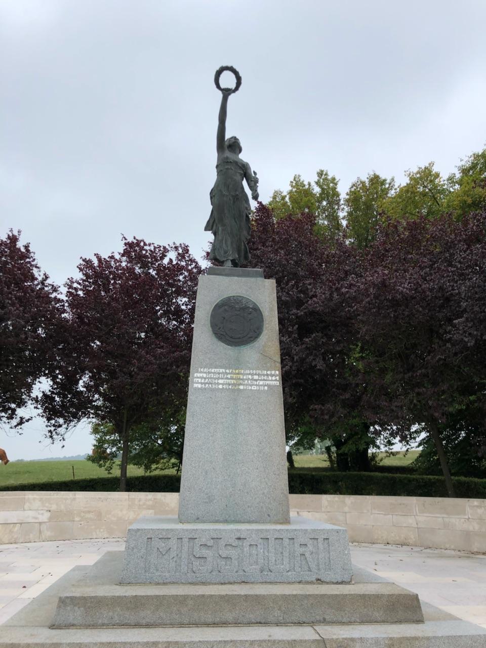 Bronze statue of a woman holding a wreath aloft on a plinth. The word 'Missouri' is engraved onto the base of the plinth.