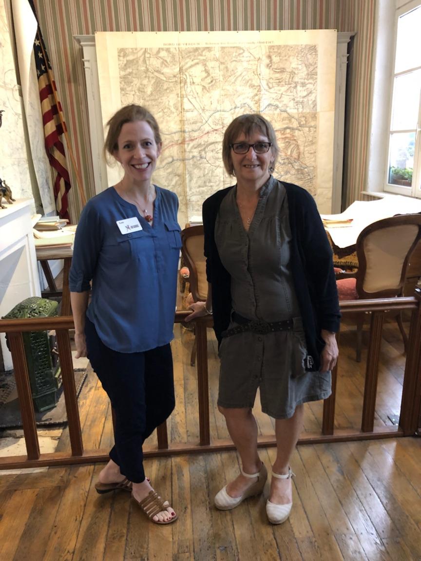 Two white women posed in front of a museum display of a WWI-era office.