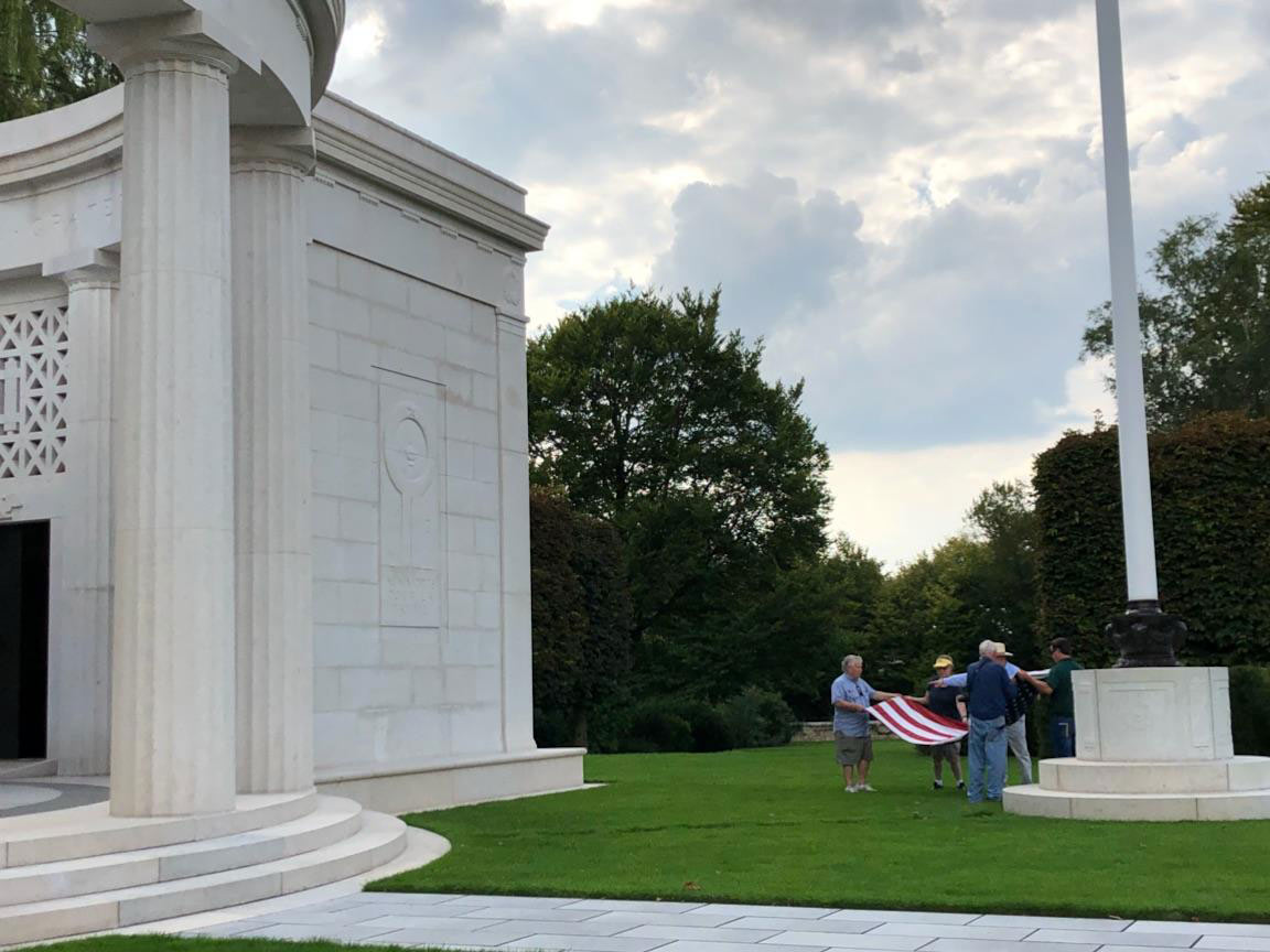 Several people carrying a U.S. flag after lowering it from the flag pole.