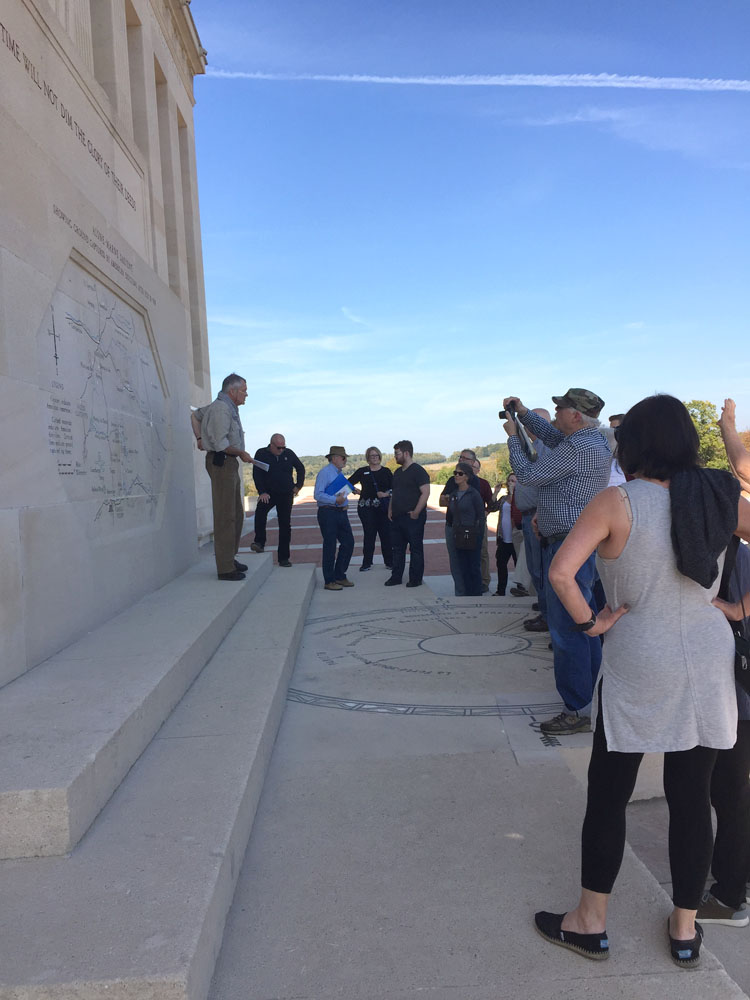 Tour group gathered around a wall of the memorial