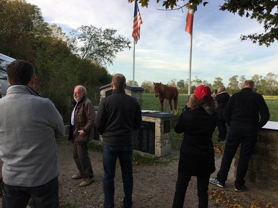 Tour group gathered around a low wall with inscriptions on it