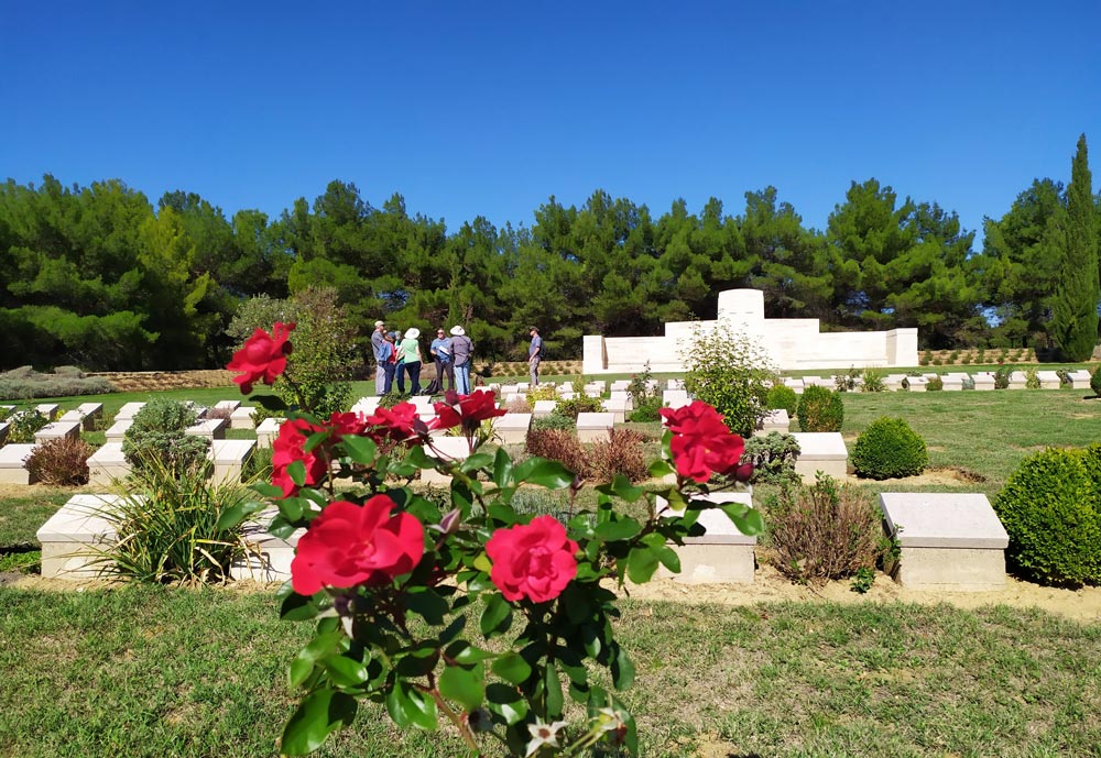 A neatly manicured cemetery with red flowers in the foreground