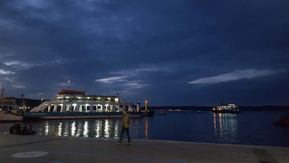 View of a large lit-up ferry boat in a bay.