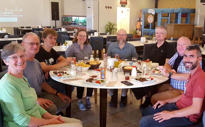 The tour group gathered around a round table loaded with food.