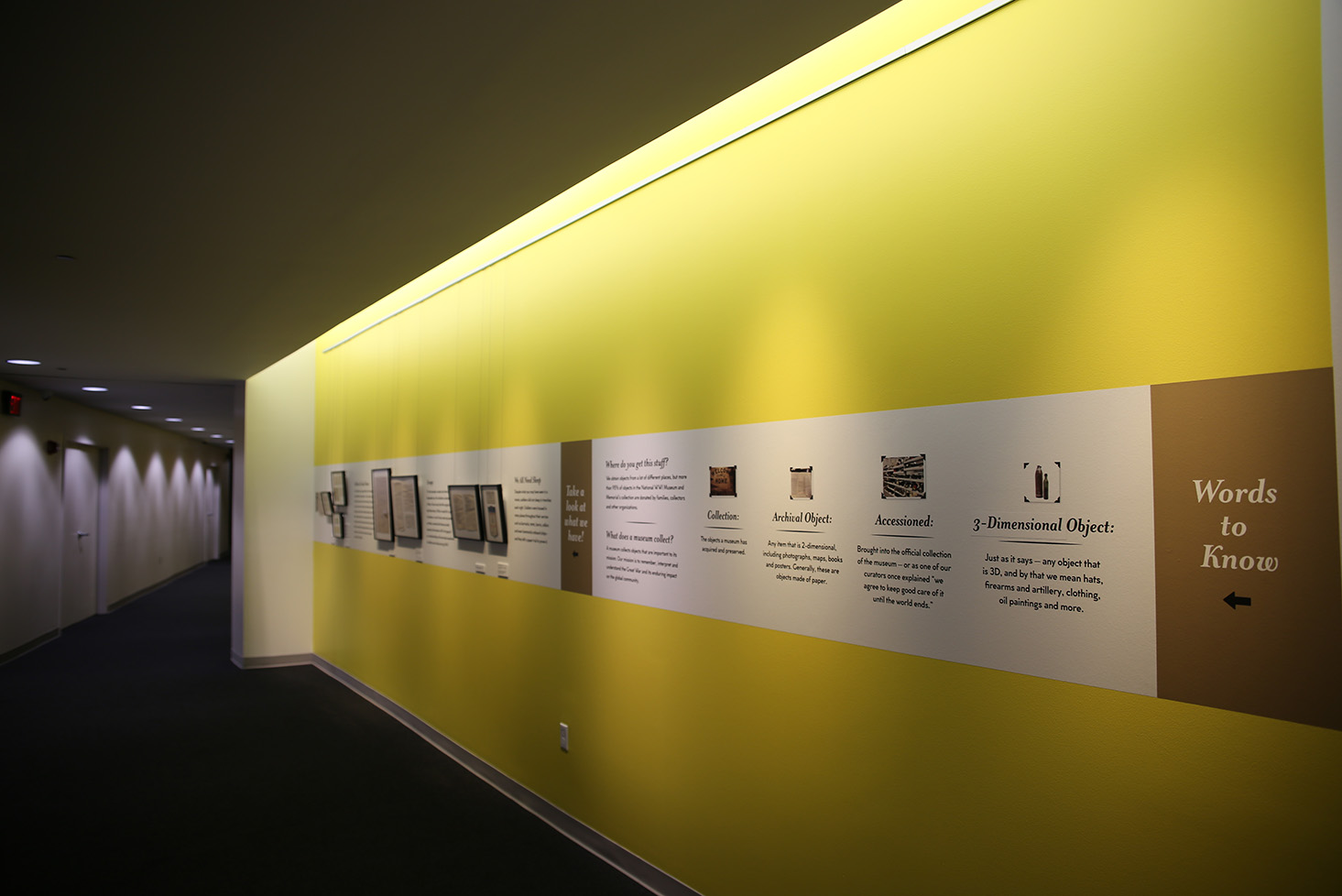 Ellis Gallery painted yellow with the exhibited objects and text hung on the walls