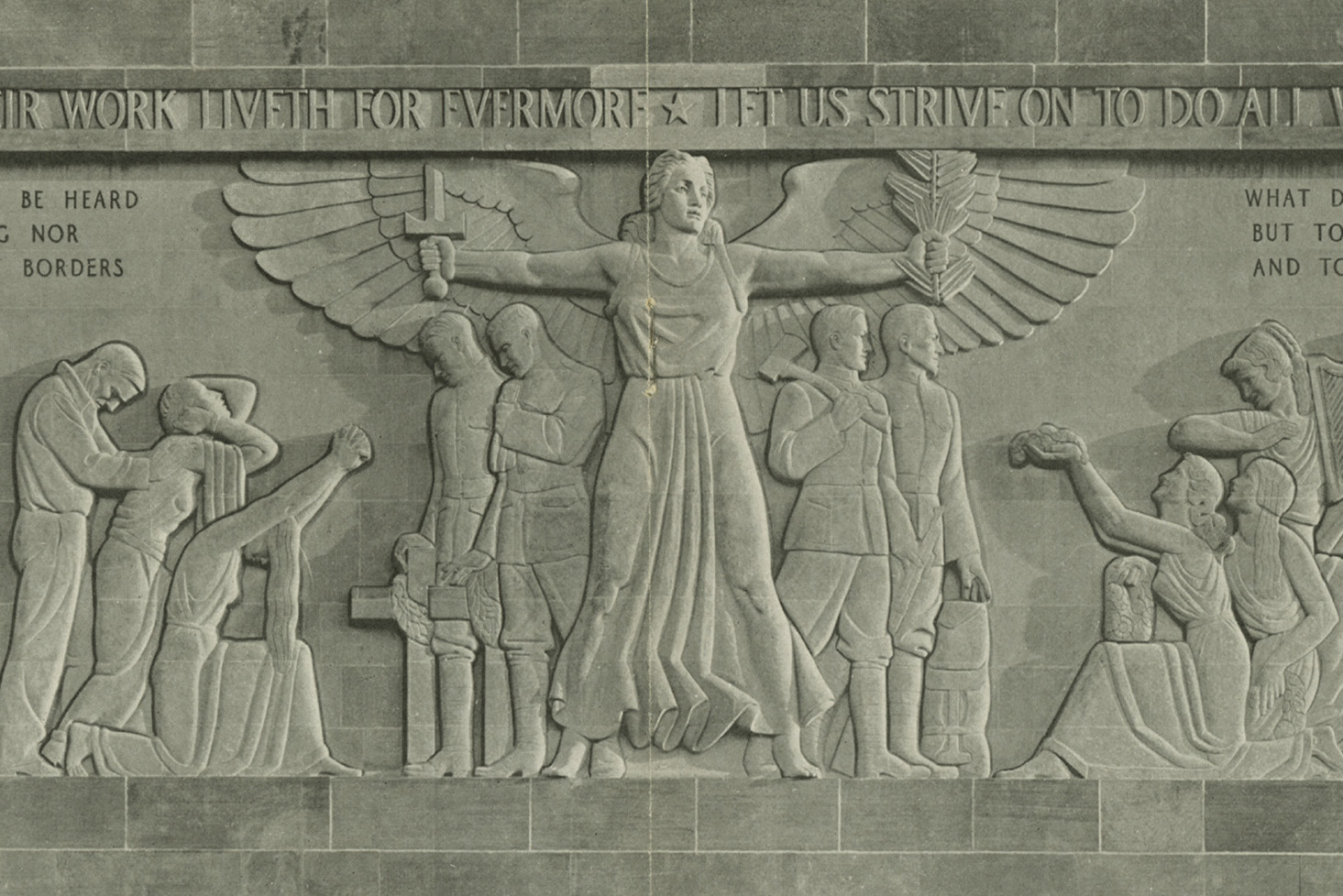Photograph of carved bas-relief figures in a stone wall. A winged figure stands in the center holding a sword and an olive branch.