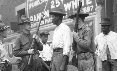 White soldiers holding rifles up, standing closely in front of Black men