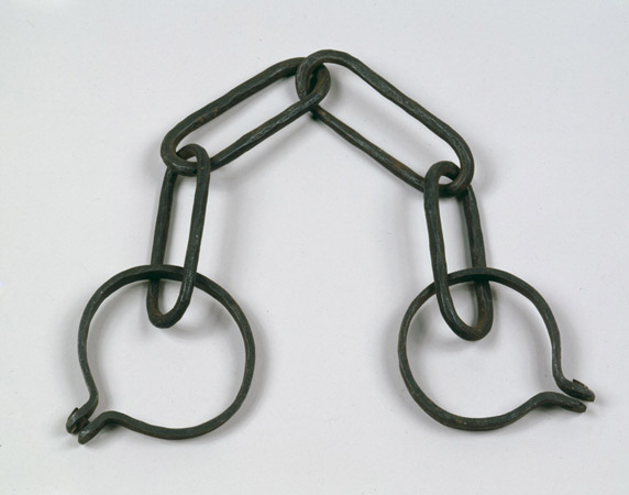 Photograph of metal shackles linked by a chain