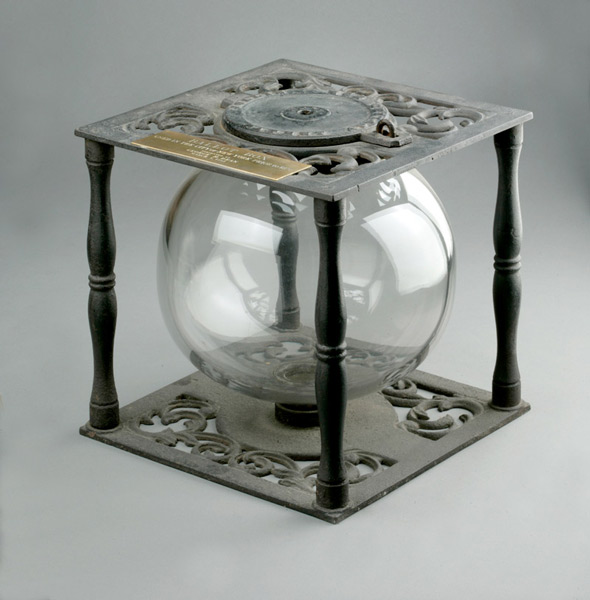 Photograph of a wrought metal ballot box. The center is a blown glass ball.