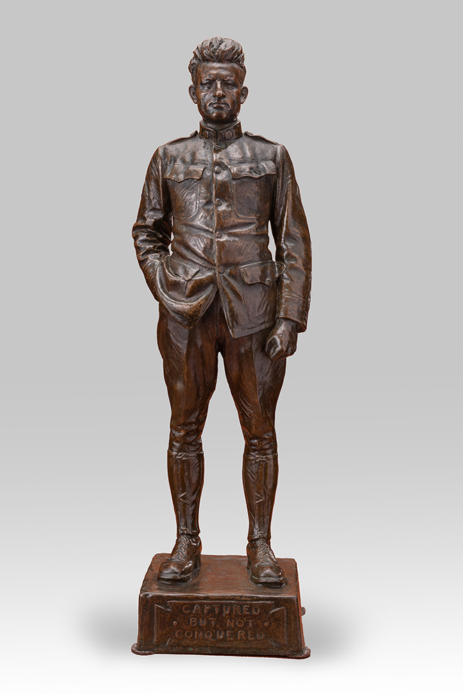 Modern photograph of a bronze statue of a male WWI soldier with one hand in his pocket
