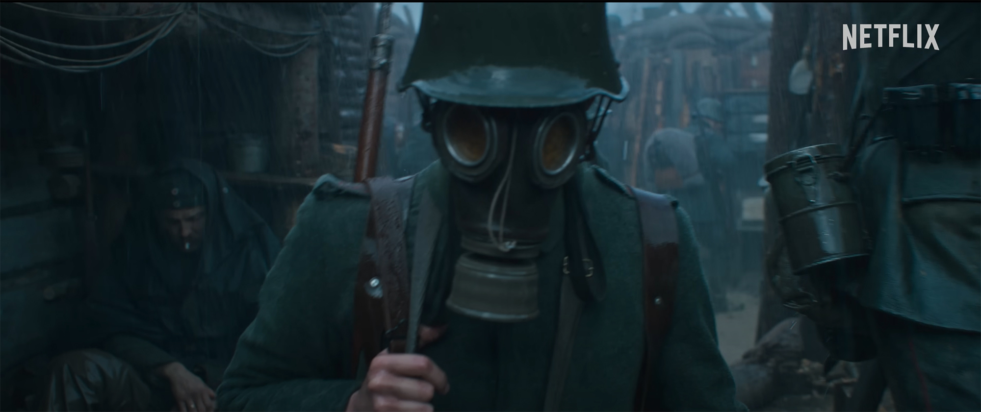 Film still showing a WWI soldier wearing a gas mask and walking forward towards the viewer