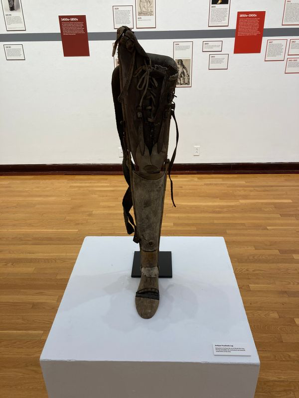 Modern photograph of a leather, wood and metal prosthetic leg on display in a museum