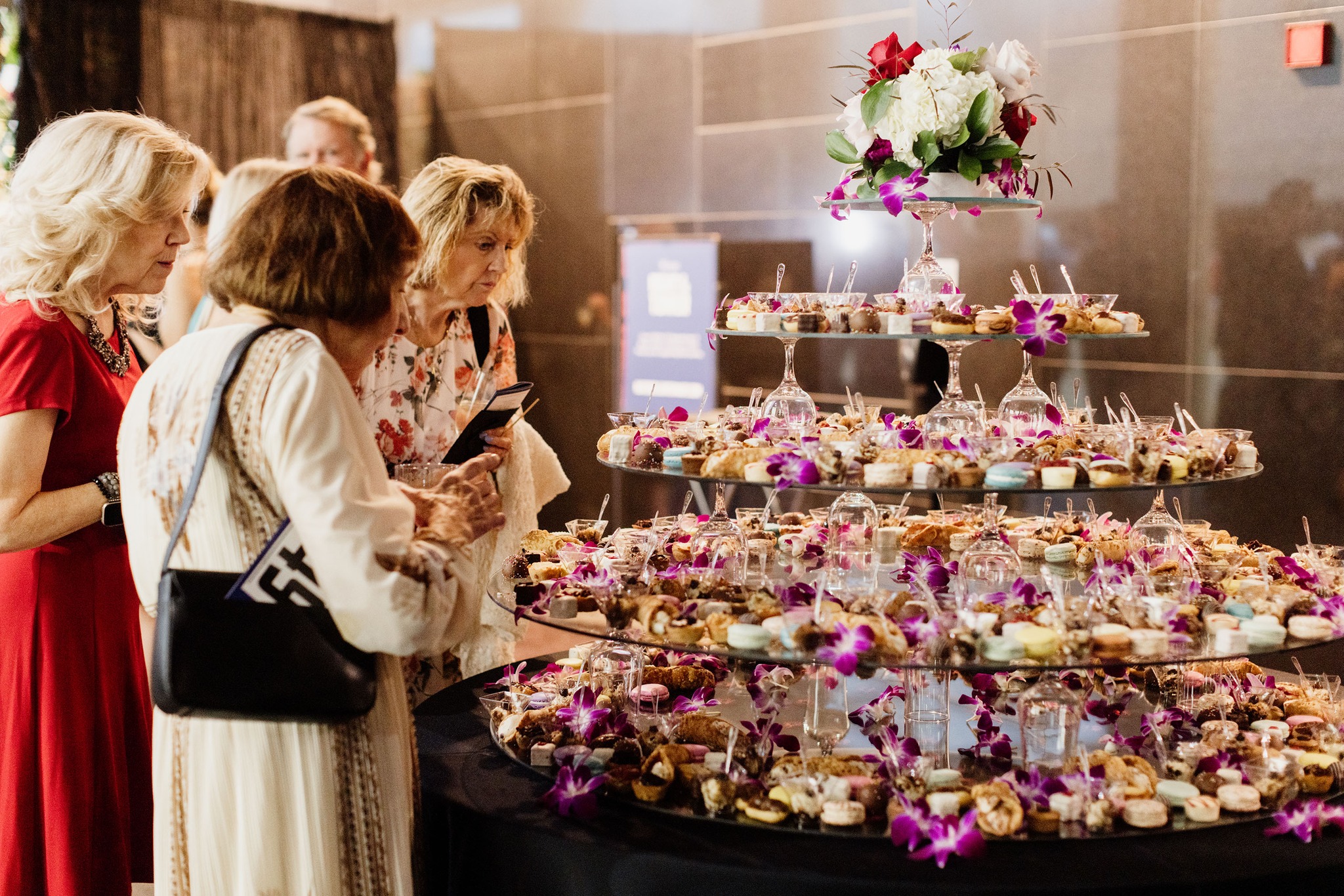 Modern photograph of several white women gathered around a tiered dessert table filled with small desserts