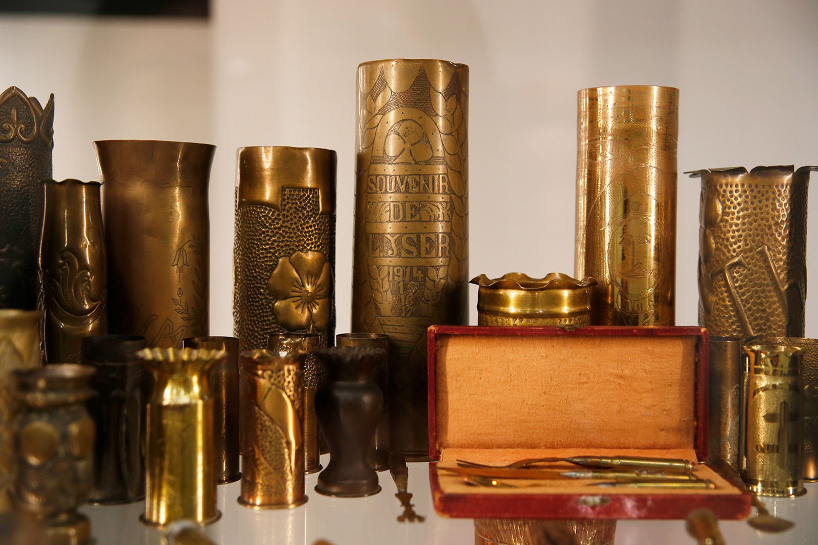 Modern photograph of a glass display case featuring an array of shell cases engraved with artwork