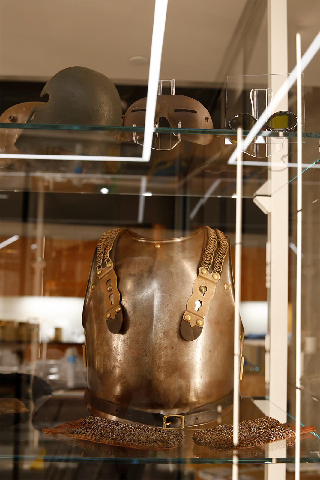 Modern photograph of a glass display case featuring a metal breastplate and chain mail