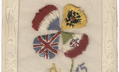 Scan of a postcard embroidered with a silk four-leaf clover. The four leaves are done in the designs and colors of the French, Russian, Italian and United Kingdom's WWI-era flags.