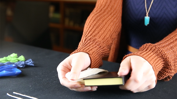 A person sliding the wrapped yarn off the small book