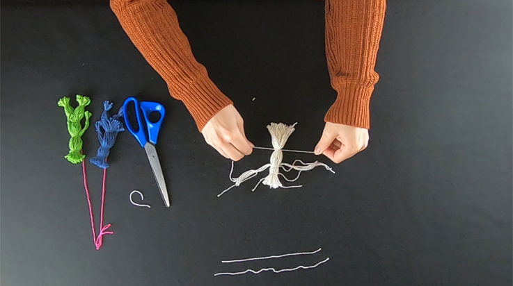 A person tying a piece of string lower down on the bundle